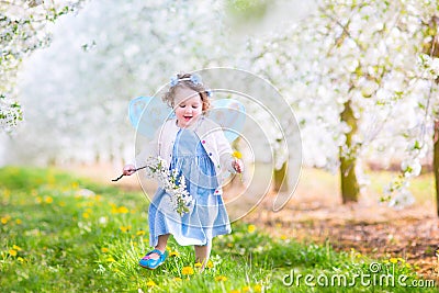 Cheerful toddler girl in fairy costume in blooming garden Stock Photo