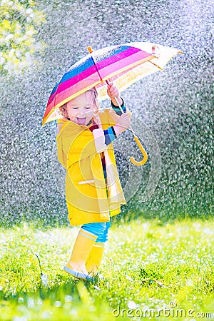 Cheerful toddler with umbrella playing in the rain Stock Photo