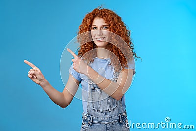 Cheerful upbeat positive summer girl redhead curly hairstyle wear denim overalls getting ready beach vacation pointing Stock Photo