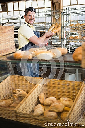 Cheerful waiter in apron holding baguettes Stock Photo