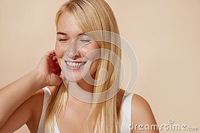 Cheerful woman with closed eyes adjusting her blond hair Stock Photo