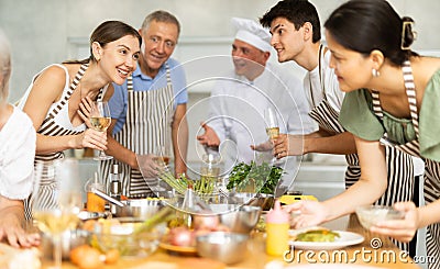 Cheerful woman drinking wine and talking during group culinary masterclass Stock Photo