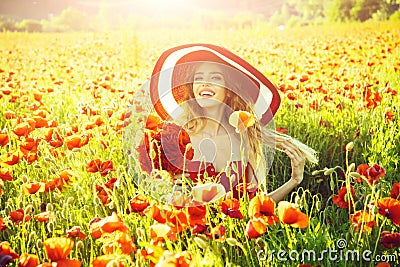 Cheerful woman on a flower field. girl in field of poppy seed in retro hat Stock Photo