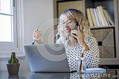 Cheerful woman freelance in smart working busy office home activity alone sitting at the desl in phone call. Concept of online Stock Photo