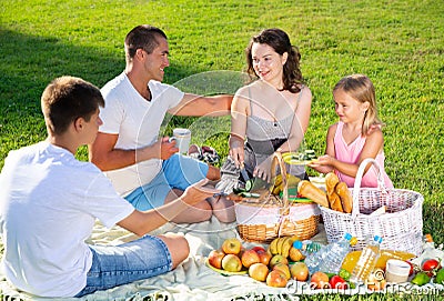 Cheerful woman picnicking with children and husband Stock Photo