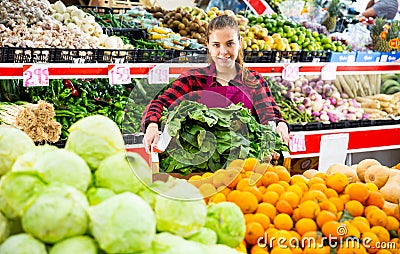 Cheerful woman seller offering for sale spinach Stock Photo