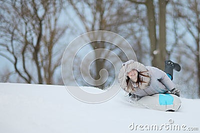 Cheerful woman sleddind down a hill; beating the winter blues Stock Photo