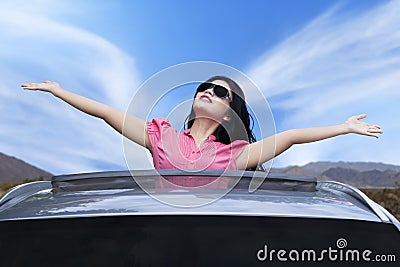 Cheerful woman standing on the sunroof Stock Photo