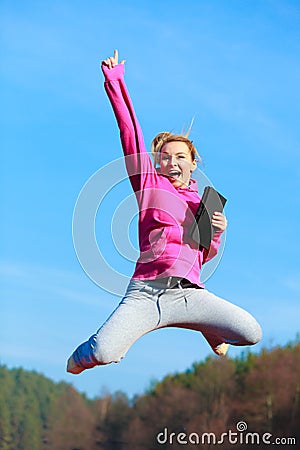 Cheerful woman teenage girl jumping with tablet outdoor Stock Photo