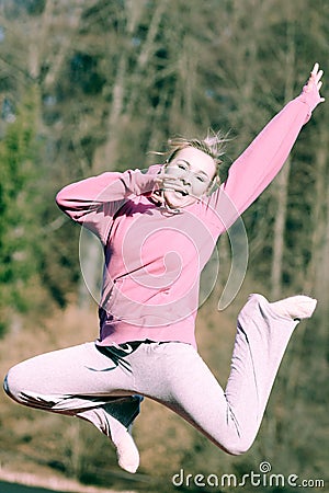 Cheerful woman teenage girl in pink tracksuit jumping outdoor Stock Photo