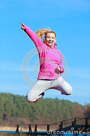 Cheerful woman teenage girl in tracksuit jumping showing outdoor Stock Photo