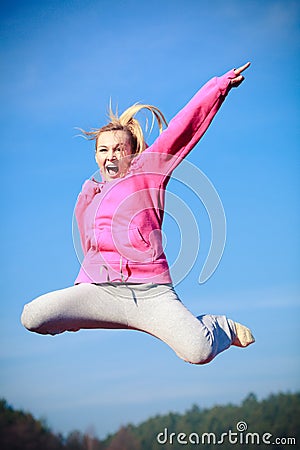 Cheerful woman teenage girl in tracksuit jumping showing outdoor Stock Photo