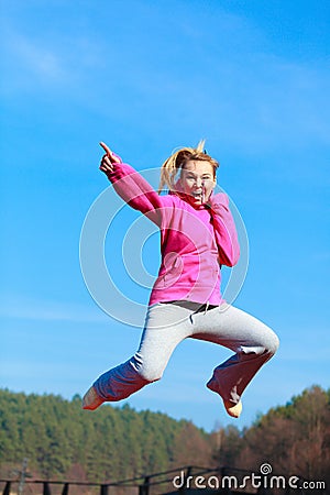 Cheerful woman teenage girl in tracksuit jumping showing outdoor Stock Photo