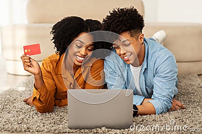 Cheerful young african american guy and woman shopaholics, use laptop Stock Photo