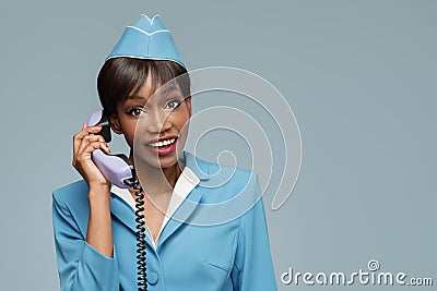 Cheerful young african stewardess talking on retro phone. Stock Photo