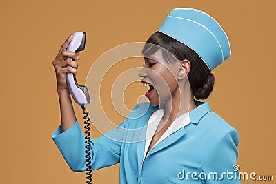 Cheerful young african stewardess talking on retro phone. Stock Photo