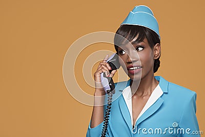 Cheerful young african stewardess talking on retro phone. Stock Photo