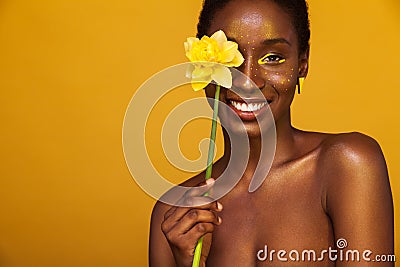 Cheerful young african woman with yellow makeup on her eyes. Female model laughing against yellow background with yellow Stock Photo