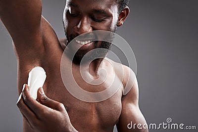 Joyful handsome afro American man using his deodorant Stock Photo