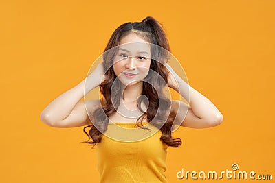 Cheerful young asian woman girl in yellow crop top posing isolated on yellow background Stock Photo