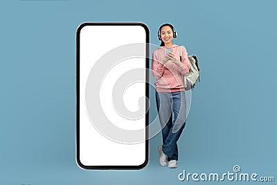 Cheerful young asian woman with headset, smartphone and backpack Stock Photo