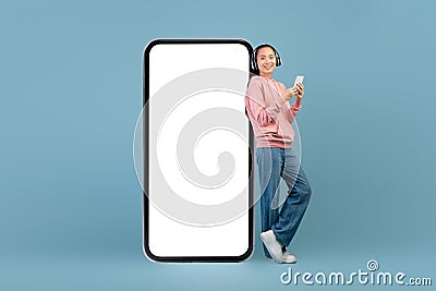 Cheerful young asian woman with headset and smartphone Stock Photo