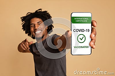 Cheerful Young Black Guy Holding Smartphone With Covid-19 Immune Passport On Screen Stock Photo