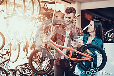 Cheerful Young Couple Chooses Kids Bicycle in Store Stock Photo