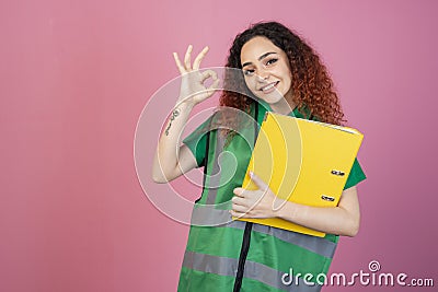 Cheerful, young lady posing indoors, looking at camera, smiling, showing alright. Stock Photo