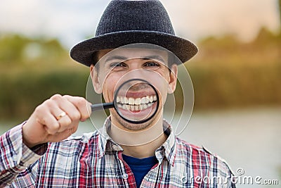 A cheerful young man holds a magnifying glass Stock Photo