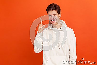 Cheerful young man pointing finger up and sincerely laughing, mischievous teenager thinking devious tricks and cheats Stock Photo