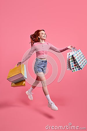 Cheerful young redhead lady jump high up speed rushing black friday addicted shopper Stock Photo