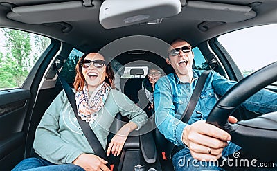 Cheerful young traditional family has a long auto journey and singing aloud the favorite song together. Safety riding car concept Stock Photo