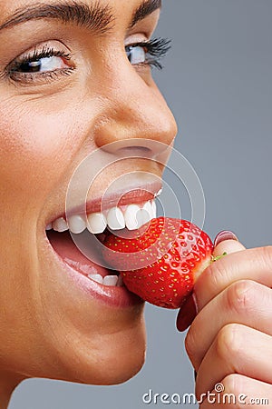 Cheerful young woman eating fresh strawberry. Detail shot of a cheerful young woman eating fresh strawberry. Stock Photo