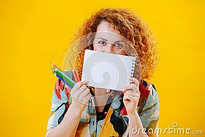 Cheerful young woman looking over her notebook, covering her face. Stock Photo