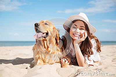 Cheerful young woman lying with her dog on the beach Stock Photo