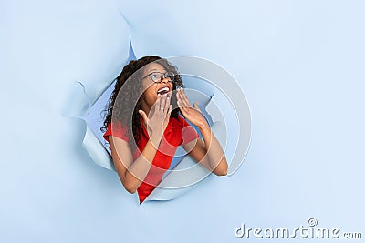 Cheerful young woman poses in torn blue paper hole background, emotional and expressive Stock Photo