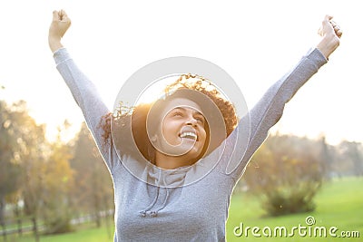 Cheerful young woman smiling with arms raised Stock Photo