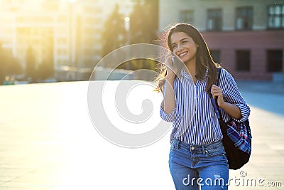 Cheerful young woman talking by phone outdoors with sunlight on her face and copy space Stock Photo