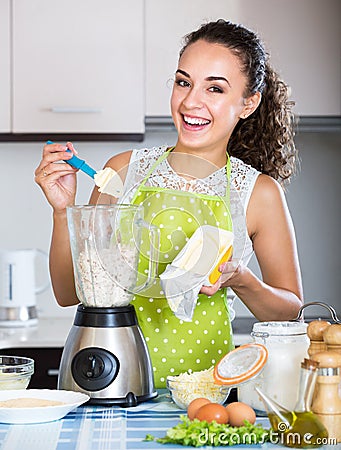 Cheerful young woman using kitchen blender Stock Photo