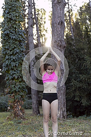 Cheerful young 8-year old child doing yoga breathe in relaxing alone, looking down, joy in the park Stock Photo