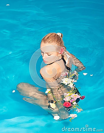 Cheerful youthful blonde girl resting while swimming pool outdoor. Happy young woman having fun at beach on sunny day Stock Photo