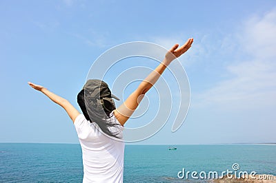 Cheering woman open arms at seaside rock Stock Photo