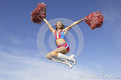 Cheerleader Jumping Midair With Pom Poms Stock Photo