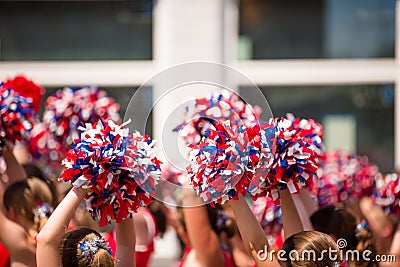 Cheerleaders Waving Red, White, and Blue Pom Poms During Fourth of July Parade Stock Photo