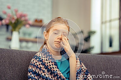 Cheerless pale young girl rubbing her face Stock Photo