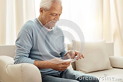 Cheerless senior man holding a pill organizer Stock Photo