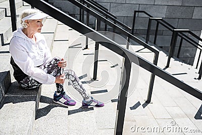 Cheerless senior woman resting after climbing up stadium ladder outdoor Stock Photo