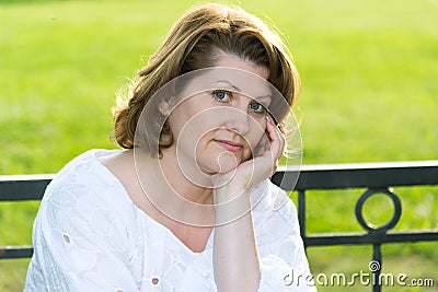 Cheerless woman in park on a bench Stock Photo