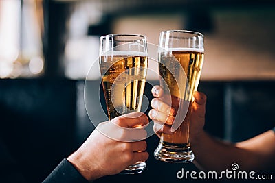 Cheers. Close-up of two men in shirts toasting with beer at the bar counter Stock Photo